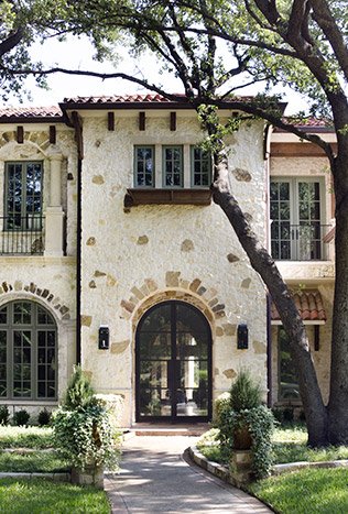 Low profile steel arched entry door stone villa by Solara Custom Living