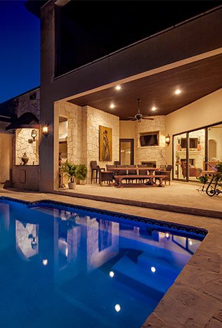 Low profile steel doors pool patio at dusk by Solara Custom Living
